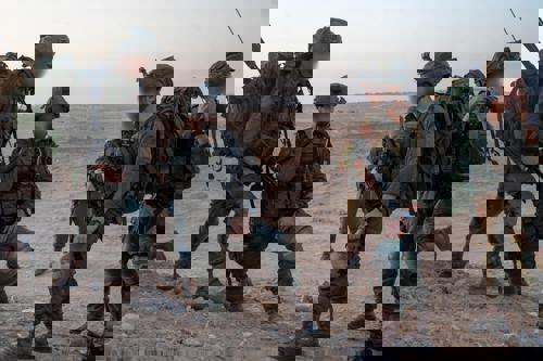 צוות של לוחמים במדבר מדברים בכריעת ברך
