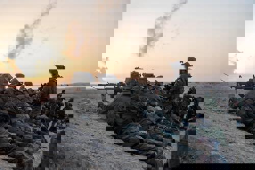 שורה של לוחמים עם נשקים בשכיבה בשקיעה